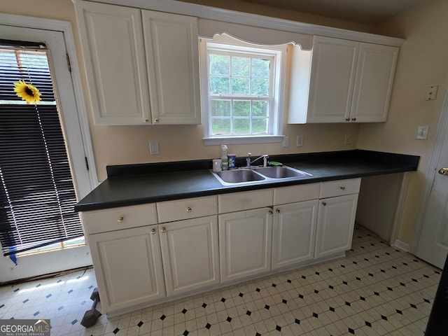 kitchen featuring a sink, white cabinets, and dark countertops