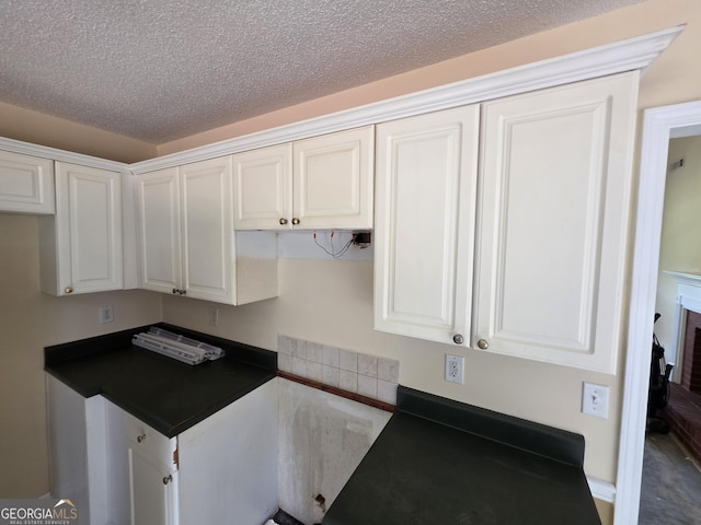 kitchen with visible vents, a textured ceiling, white cabinets, and dark countertops