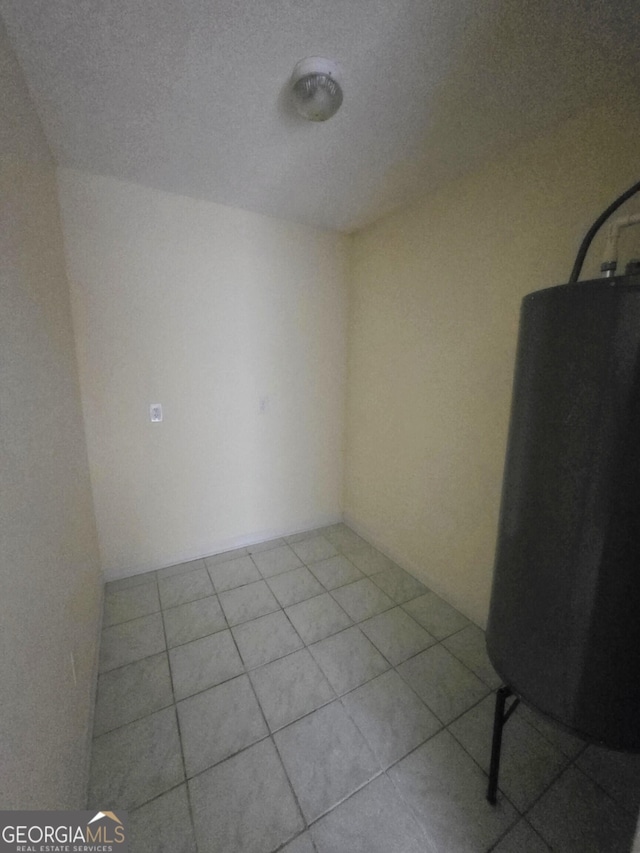 empty room featuring tile patterned floors and water heater