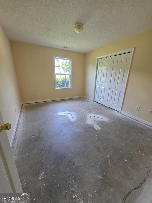 unfurnished bedroom featuring baseboards, a closet, and a textured ceiling