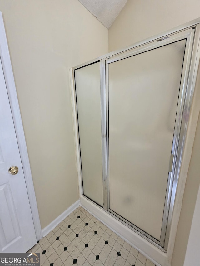 bathroom with baseboards, tile patterned flooring, vaulted ceiling, and a shower stall