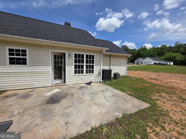 back of property with central AC unit, a patio area, and a yard