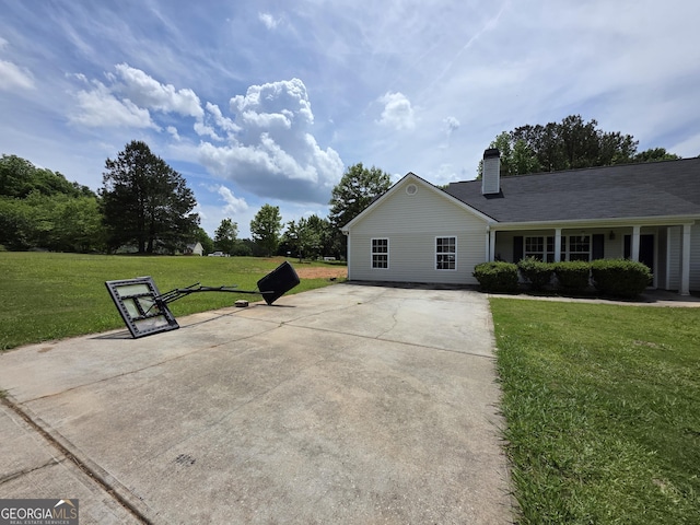 view of side of home featuring a lawn, driveway, and a chimney