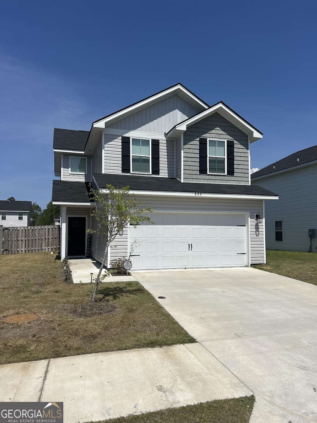 view of front of property with an attached garage, board and batten siding, fence, and concrete driveway