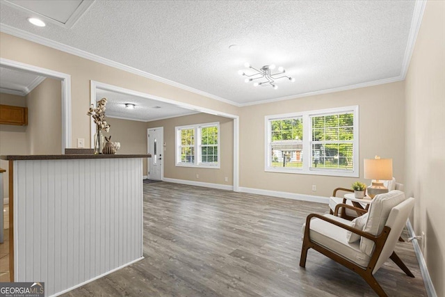 sitting room with crown molding, a textured ceiling, baseboards, and wood finished floors