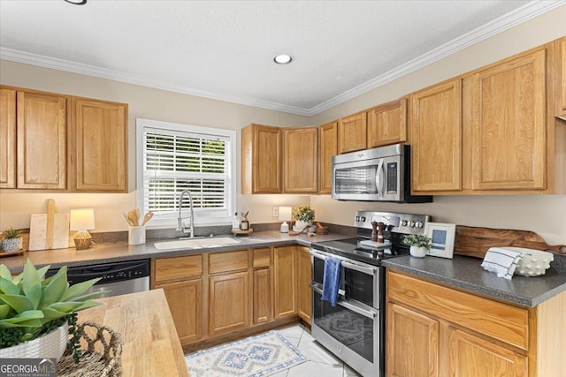 kitchen featuring crown molding, dark countertops, a sink, stainless steel appliances, and recessed lighting