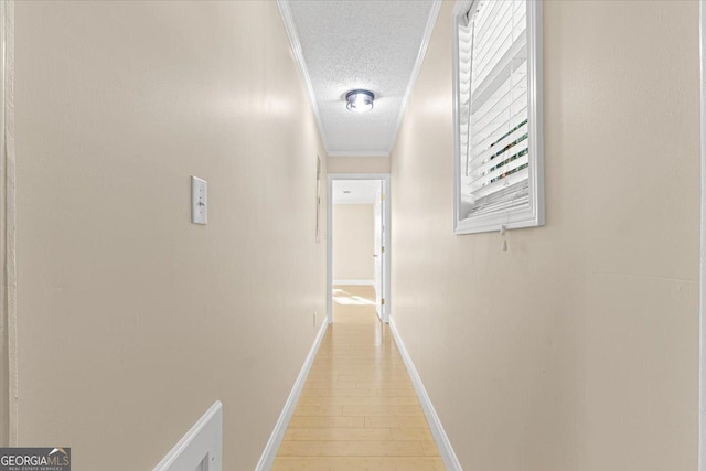 corridor featuring light wood-type flooring, a textured ceiling, and baseboards