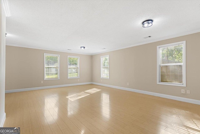 empty room with crown molding, a textured ceiling, baseboards, and light wood finished floors