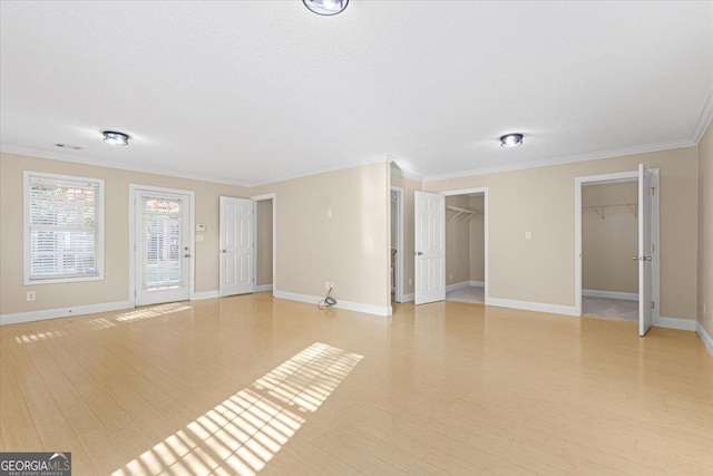 unfurnished living room with crown molding, baseboards, visible vents, and light wood-style floors