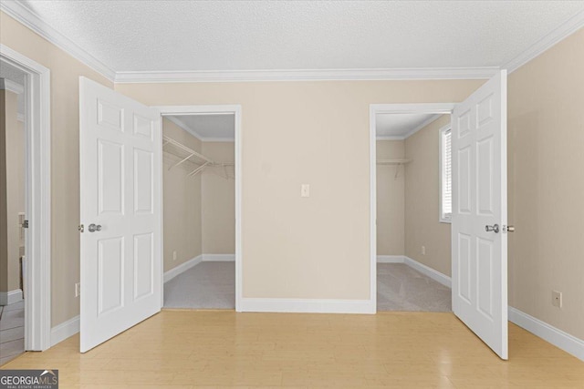 unfurnished bedroom featuring baseboards, light wood finished floors, and a walk in closet