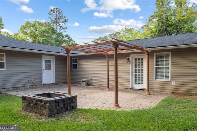 back of house with a fire pit, a pergola, a patio, roof with shingles, and a lawn