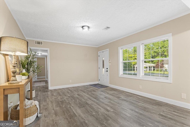 foyer entrance with a textured ceiling, baseboards, wood finished floors, visible vents, and ornamental molding