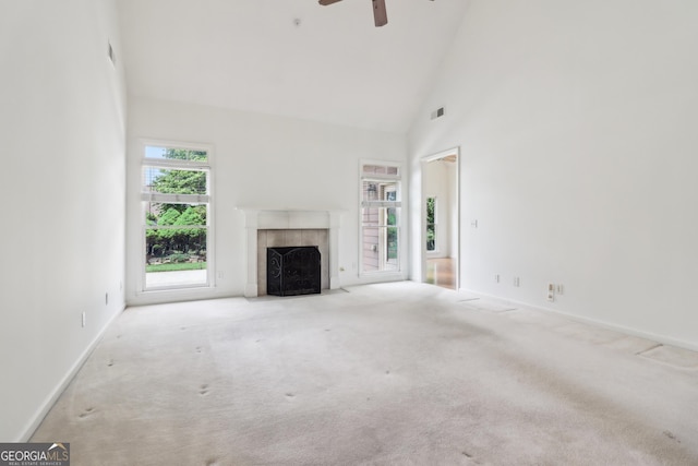 unfurnished living room featuring carpet flooring, high vaulted ceiling, a ceiling fan, and a tile fireplace