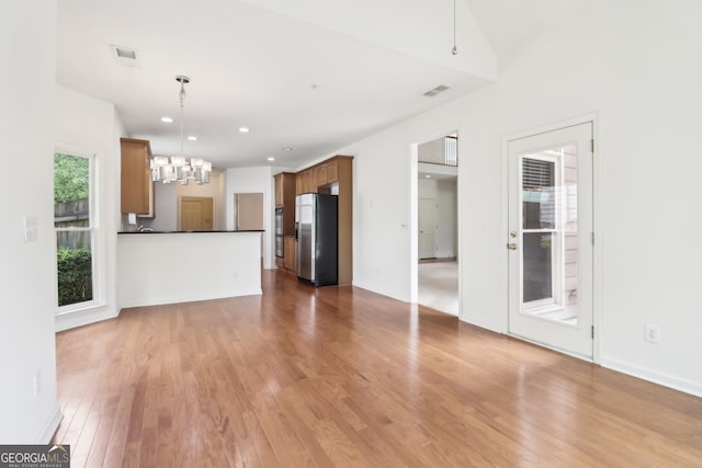 unfurnished living room featuring a chandelier, visible vents, wood finished floors, and recessed lighting