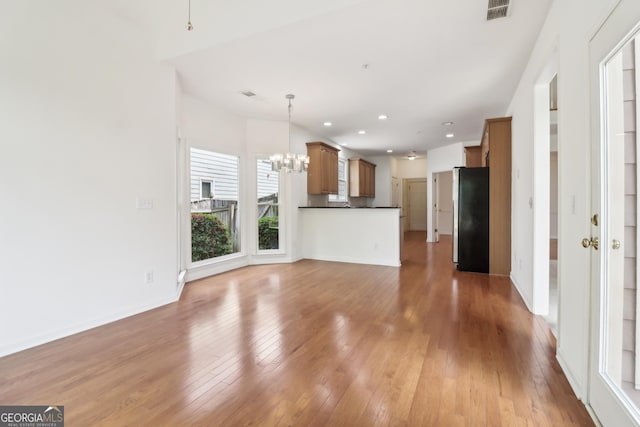 unfurnished living room with visible vents, light wood-type flooring, baseboards, a chandelier, and recessed lighting
