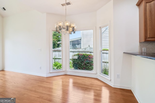 unfurnished dining area with light wood-style floors, an inviting chandelier, plenty of natural light, and visible vents
