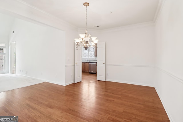 unfurnished dining area featuring baseboards, ornamental molding, a chandelier, and wood finished floors