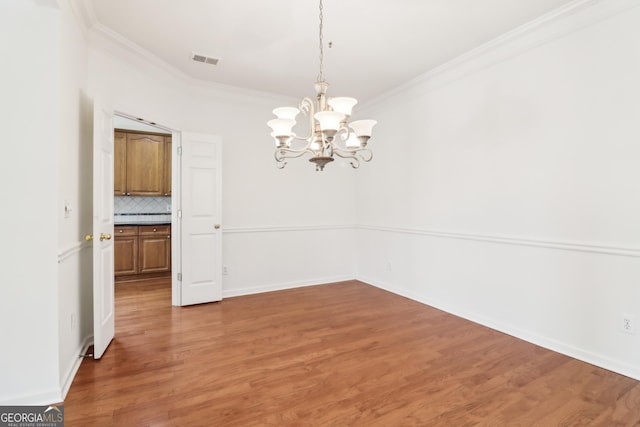 unfurnished dining area with light wood-type flooring, ornamental molding, a chandelier, and visible vents