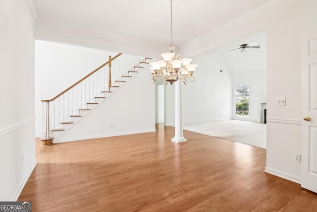 unfurnished dining area with ornamental molding, ceiling fan with notable chandelier, stairs, wood finished floors, and a fireplace