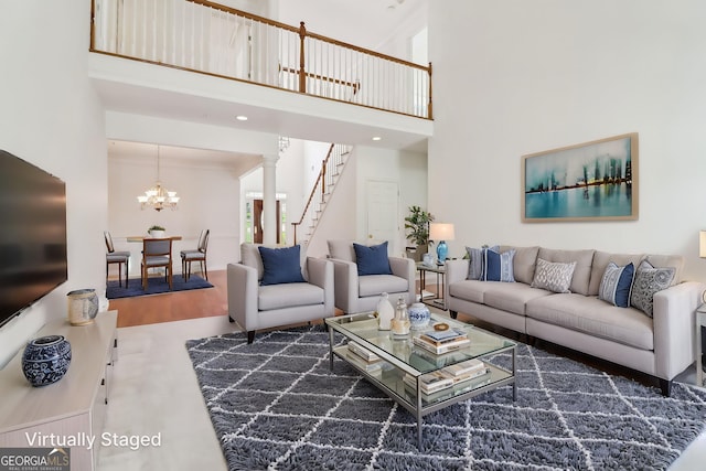 living room featuring stairs, crown molding, an inviting chandelier, and a towering ceiling