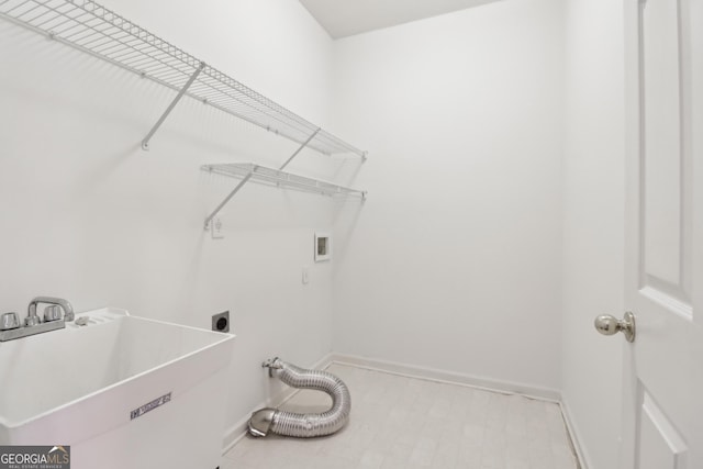 washroom featuring laundry area, baseboards, hookup for a washing machine, a sink, and hookup for an electric dryer