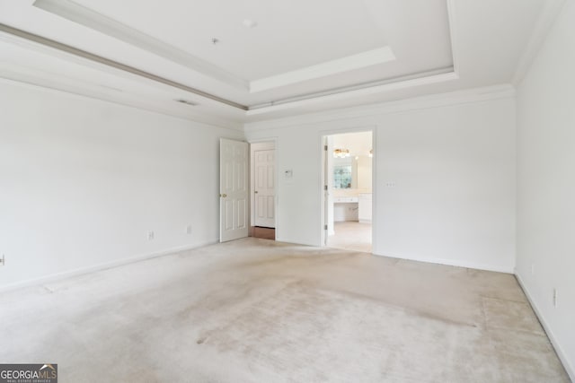 unfurnished room featuring crown molding, a raised ceiling, baseboards, and light colored carpet
