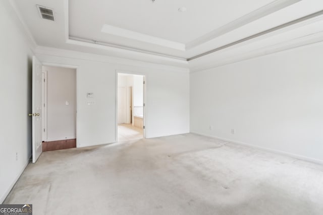 unfurnished bedroom with visible vents, crown molding, a raised ceiling, light carpet, and ensuite bath