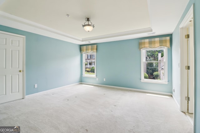 unfurnished bedroom with carpet floors, a tray ceiling, visible vents, and multiple windows