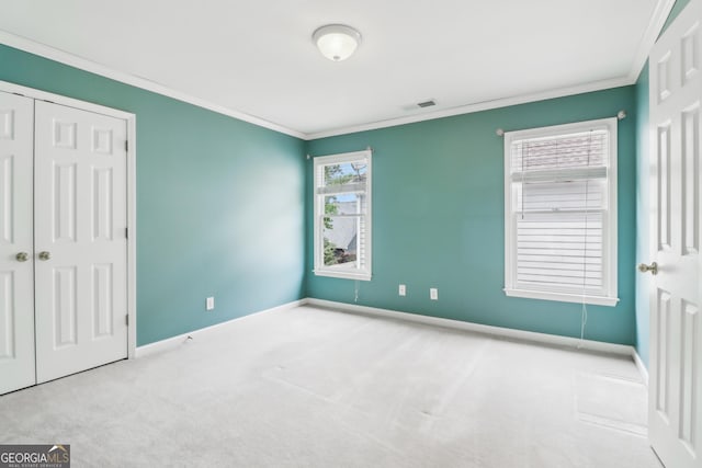 unfurnished bedroom with carpet, baseboards, visible vents, ornamental molding, and a closet