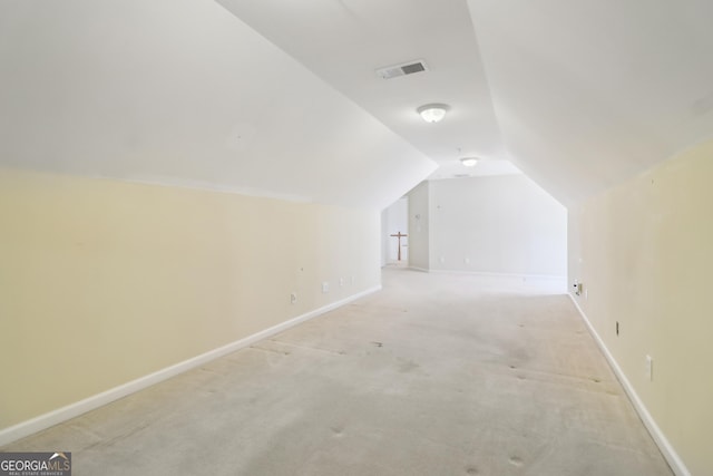 additional living space with baseboards, visible vents, light carpet, and lofted ceiling