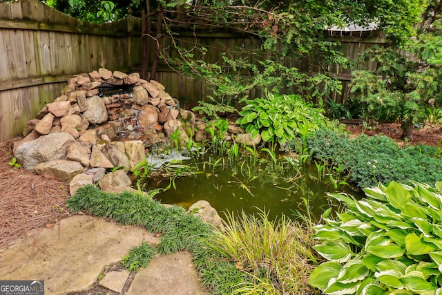 view of yard featuring a garden pond and fence
