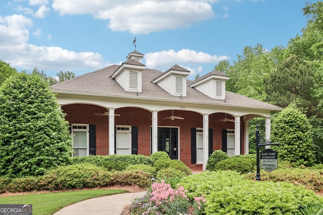 view of front of property with covered porch, brick siding, a ceiling fan, and roof with shingles