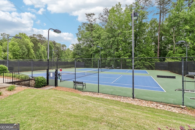 view of tennis court featuring a lawn and fence