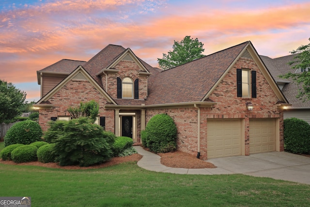 traditional-style house featuring brick siding, driveway, a front yard, and roof with shingles