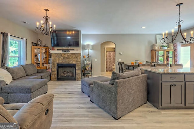346 Woodland Ln, Hayesville, NC 28904 - living area featuring a stone fireplace, arched walkways, light wood-style flooring, and a chandelier