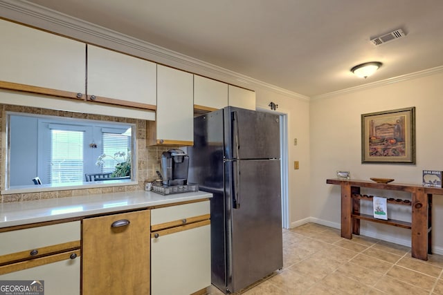 kitchen featuring visible vents, freestanding refrigerator, ornamental molding, light countertops, and white cabinetry
