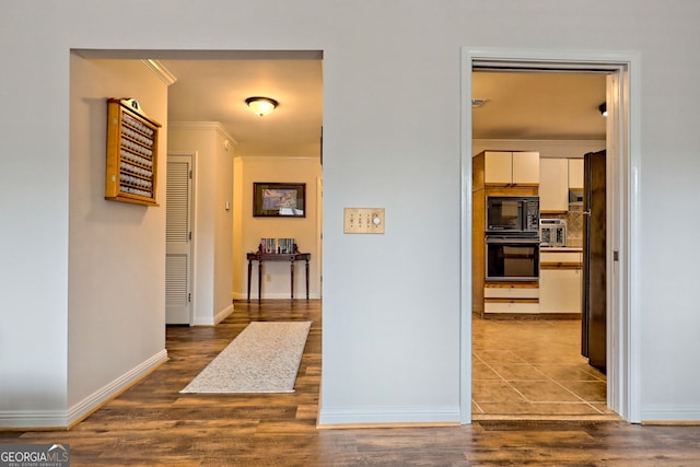 hallway with crown molding, baseboards, and wood finished floors