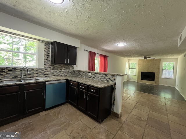 kitchen with a ceiling fan, a peninsula, a textured ceiling, a sink, and dishwasher