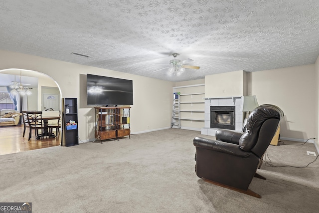 142 Old Hampton Way, Hampton, GA 30228 - living room featuring visible vents, a fireplace, arched walkways, carpet flooring, and ceiling fan with notable chandelier