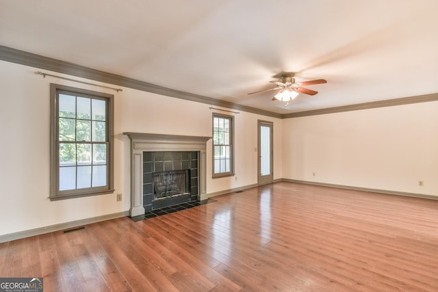 unfurnished living room with visible vents, crown molding, wood finished floors, a fireplace, and a ceiling fan