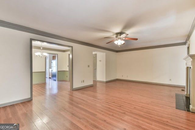 unfurnished living room featuring crown molding, light wood-style floors, ceiling fan with notable chandelier, baseboards, and a fireplace with flush hearth