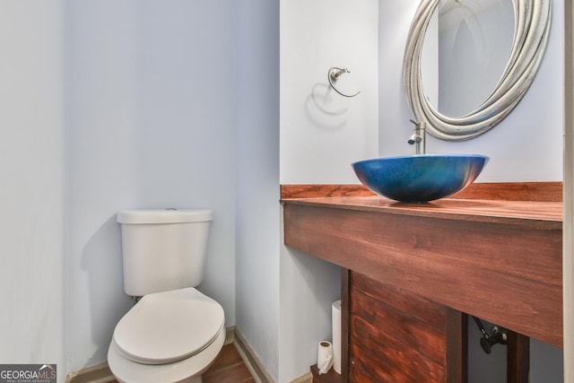 half bathroom featuring toilet, baseboards, and a sink