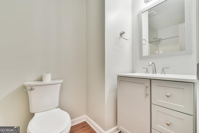 bathroom with toilet, baseboards, wood finished floors, and vanity