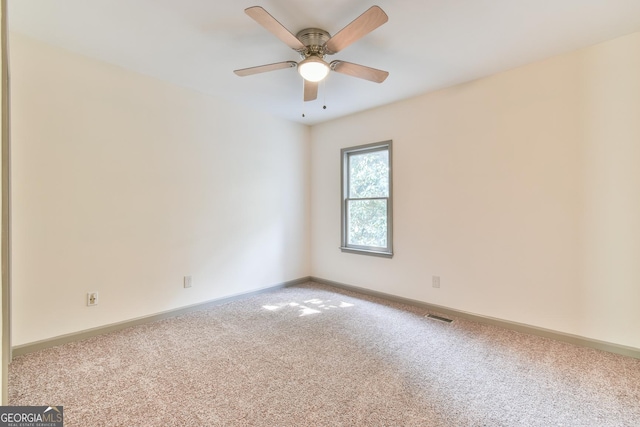 spare room with carpet floors, baseboards, ceiling fan, and visible vents