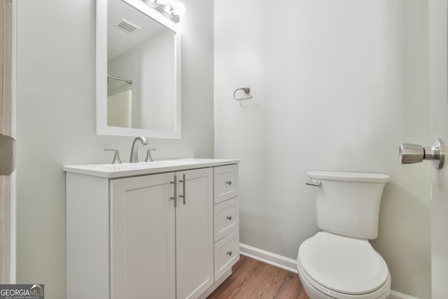 bathroom featuring visible vents, wood finished floors, baseboards, vanity, and toilet