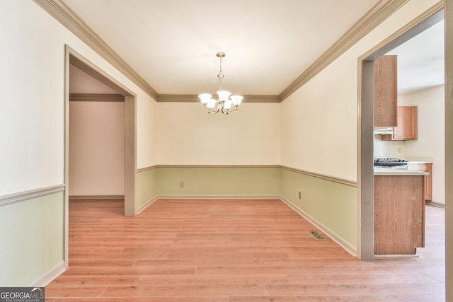 unfurnished dining area with ornamental molding, light wood-style flooring, a chandelier, and visible vents