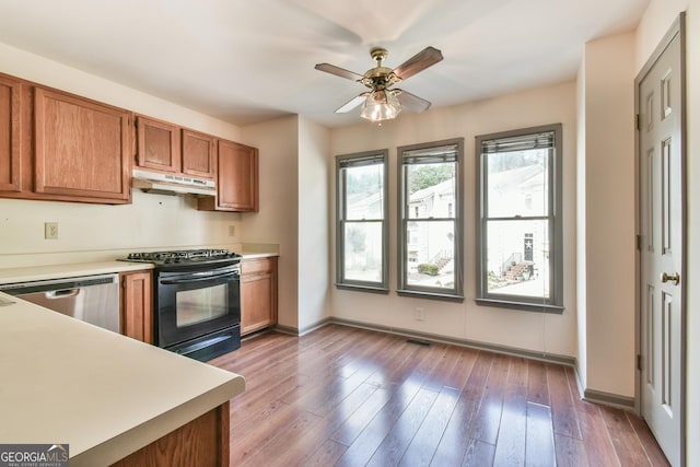 kitchen with black gas range, brown cabinetry, stainless steel dishwasher, light countertops, and under cabinet range hood