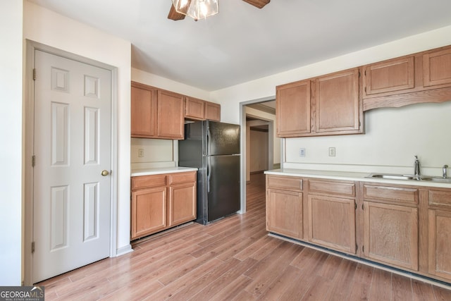 kitchen featuring ceiling fan, a sink, light countertops, freestanding refrigerator, and light wood-style floors