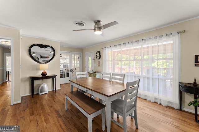 dining room featuring crown molding, light wood-style floors, a ceiling fan, and visible vents