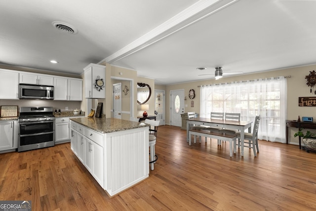 kitchen with stone counters, white cabinets, stainless steel appliances, and light wood-type flooring